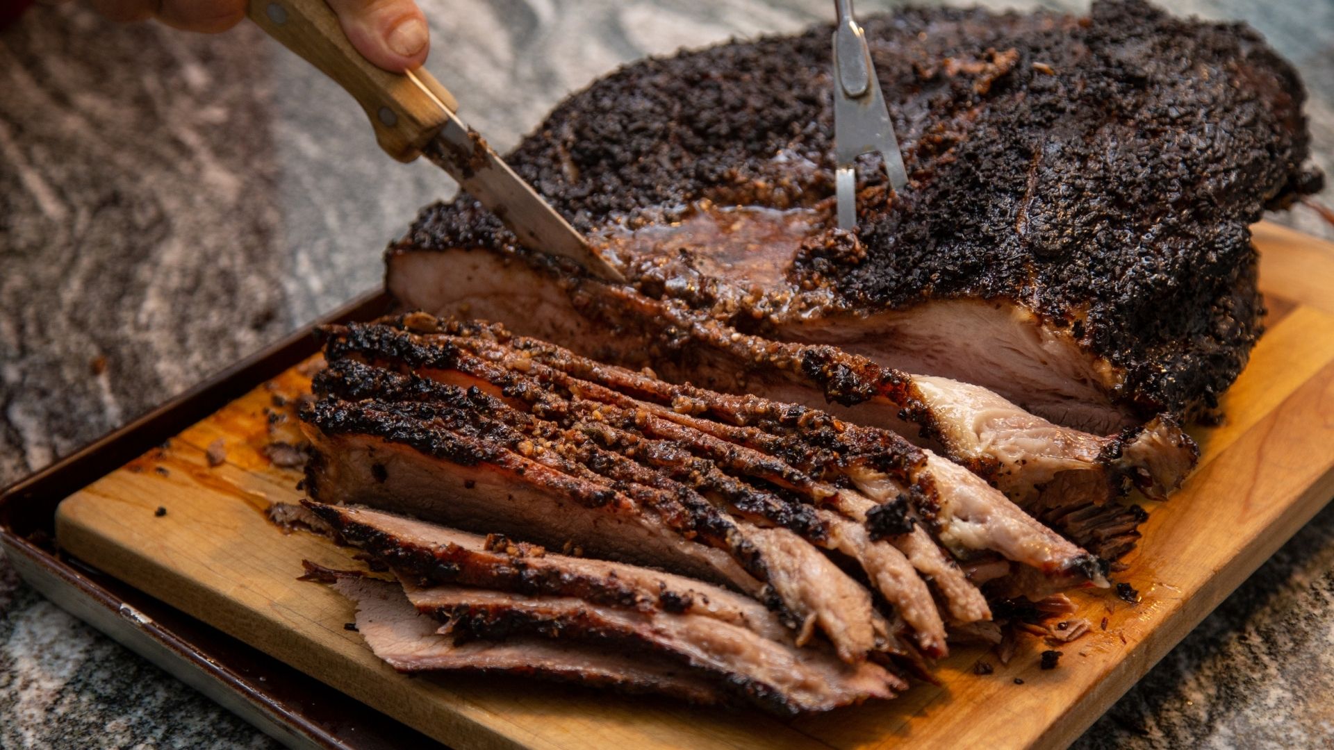 A juicy, well-seasoned Southwest-style brisket being sliced on a wooden cutting board. The brisket has a dark, flavorful crust and tender, moist meat with a beautiful smoke ring. A carving knife and fork are being used to cut through the brisket, showcasing its deliciously marbled texture.