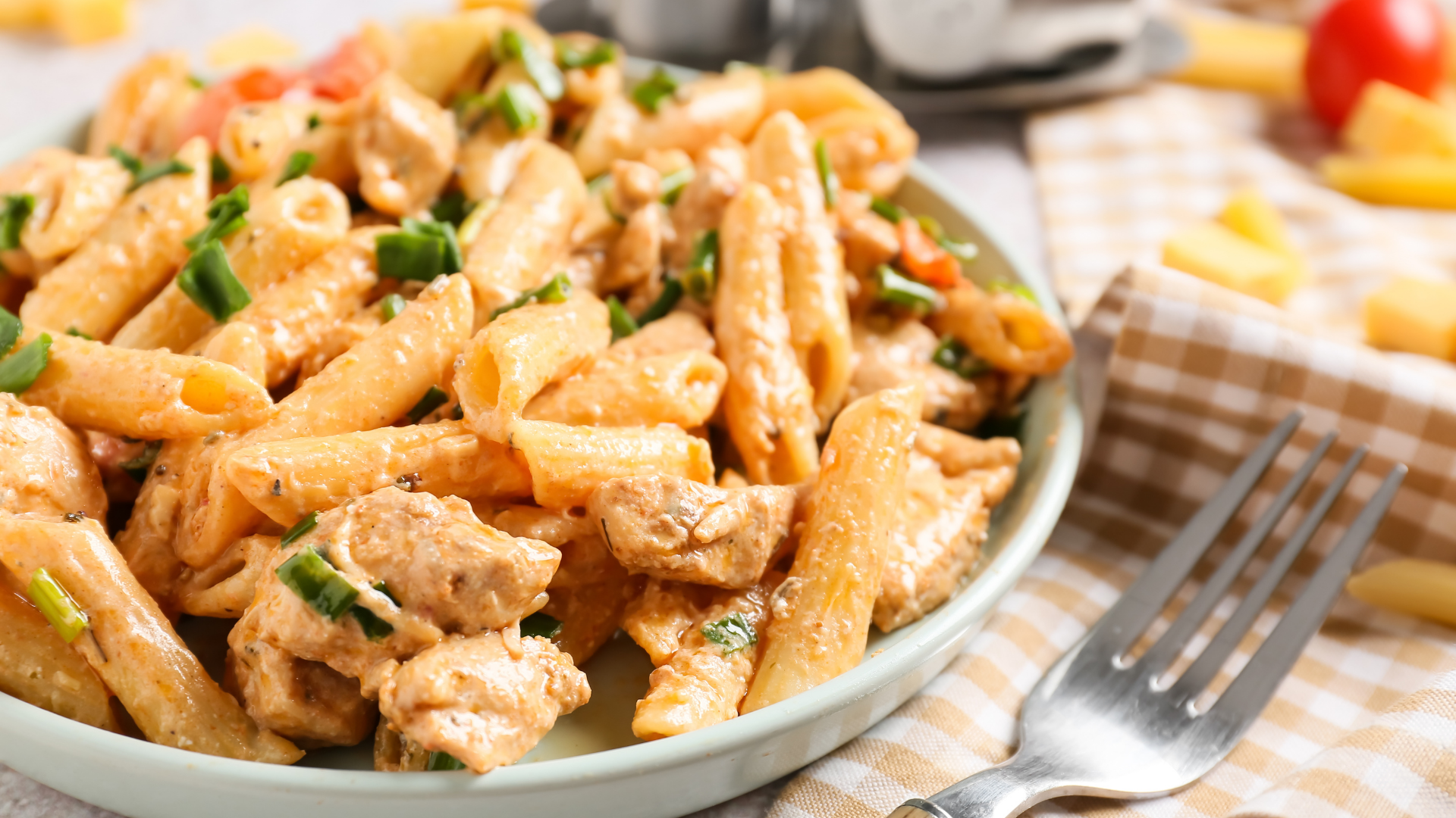 A plate of creamy Cajun chicken pasta with penne noodles, tender chicken pieces, and chopped green onions.