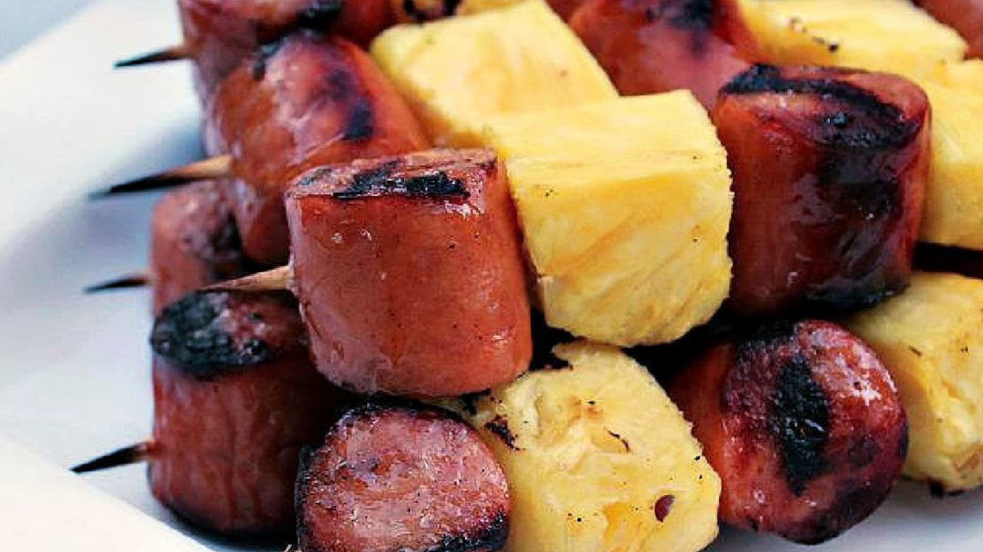 Bratwurst slices and fresh pineapple chunks grilled on skewers, showcasing caramelized edges and a smoky finish.
