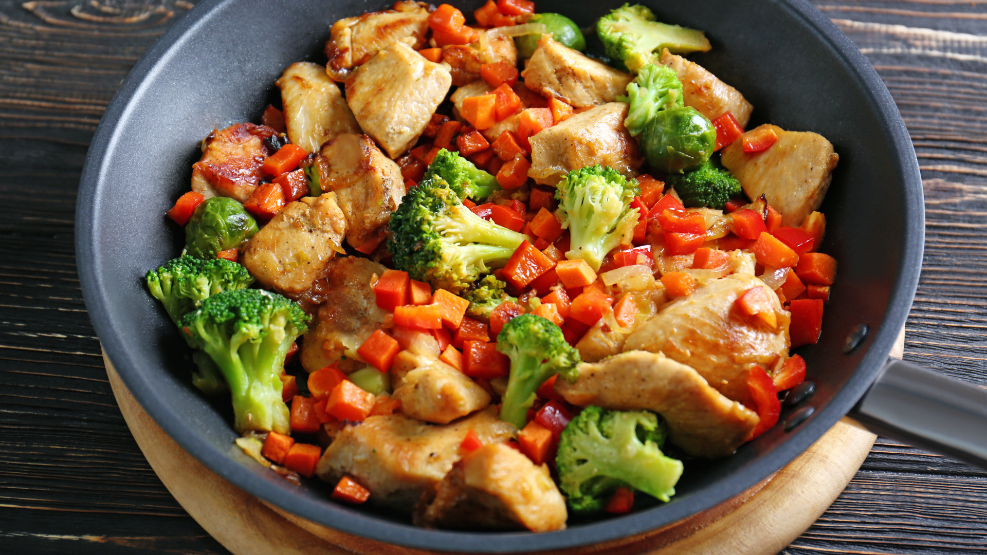 Quick chicken stir-fry with diced chicken breast, broccoli, carrots, and red bell peppers in a savory sauce, served in a skillet.